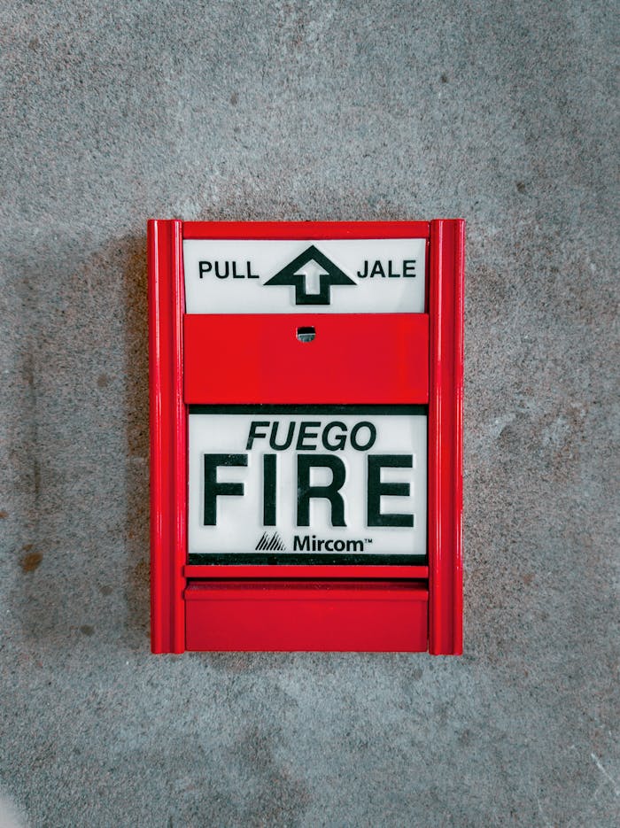 Red fire alarm system with text 'FUEGO FIRE'. Promotes safety and protection.
