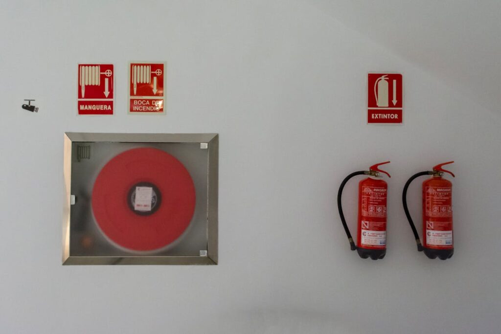 Fire safety setup with extinguishers and hose reel on a white wall for emergency preparedness.