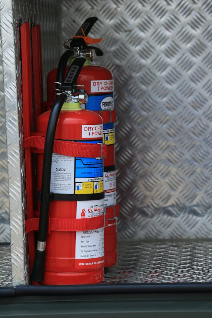 Close-up view of fire extinguishers secured inside a storage compartment with metal texture.