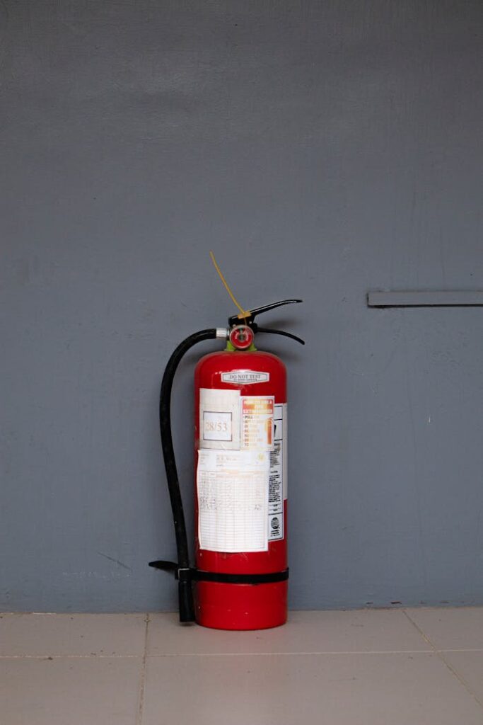 Red fire extinguisher positioned against a gray wall showing safety equipment