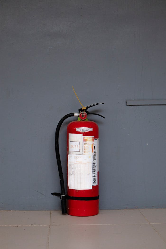 Red fire extinguisher positioned against a gray wall showing safety equipment